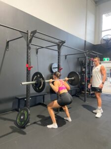 Jacob Watson teaching client how to back squat